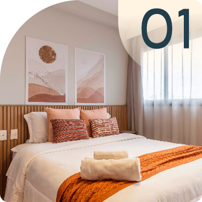 Bedroom with bed, pillows, artwork, and towels; orange and beige color scheme;