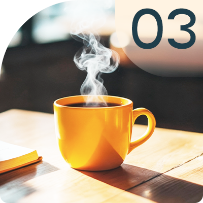 Yellow coffee mug with steam rising, on a wooden table. Number 03 in the upper right.