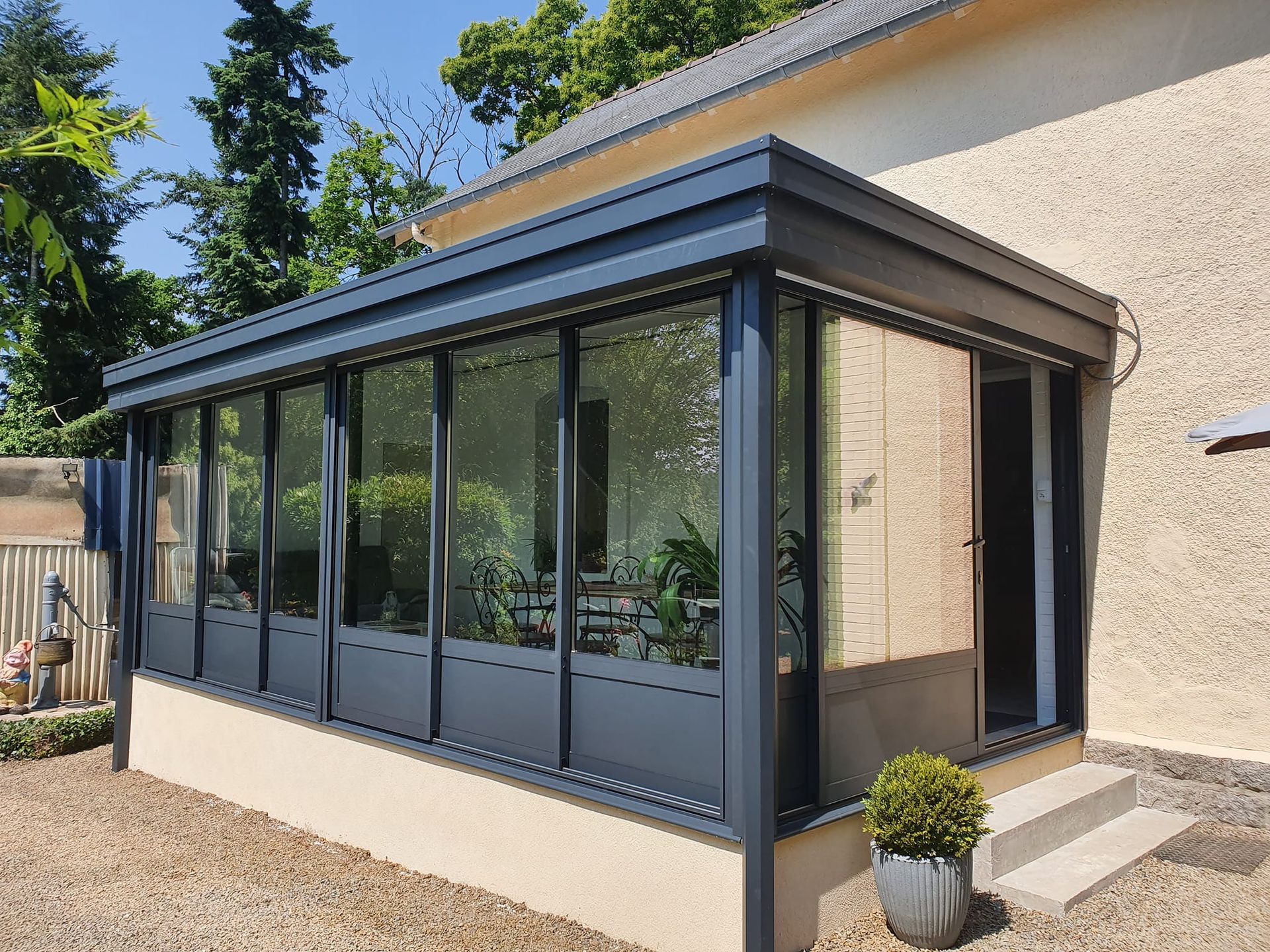 Véranda en aluminium avec un arbuste en pot devant