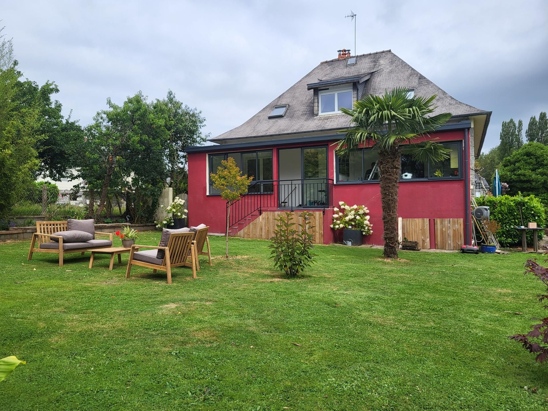Maison avec un salon de jardin et une véranda à la façade rouge