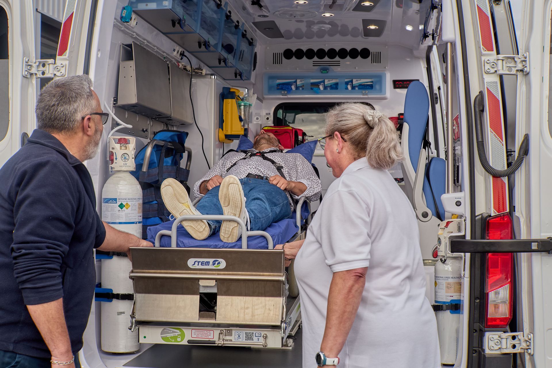 Patient allongé sur un brancard chargé dans une ambulance et une ambulancière