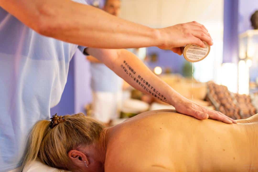 Un masseur applique de l’huile sur le dos d’un client dans un spa
