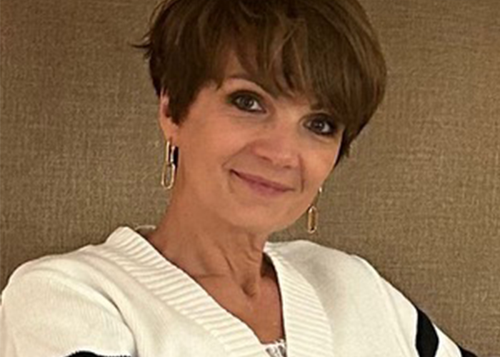 Femme souriante en pull blanc sur fond beige texturé
