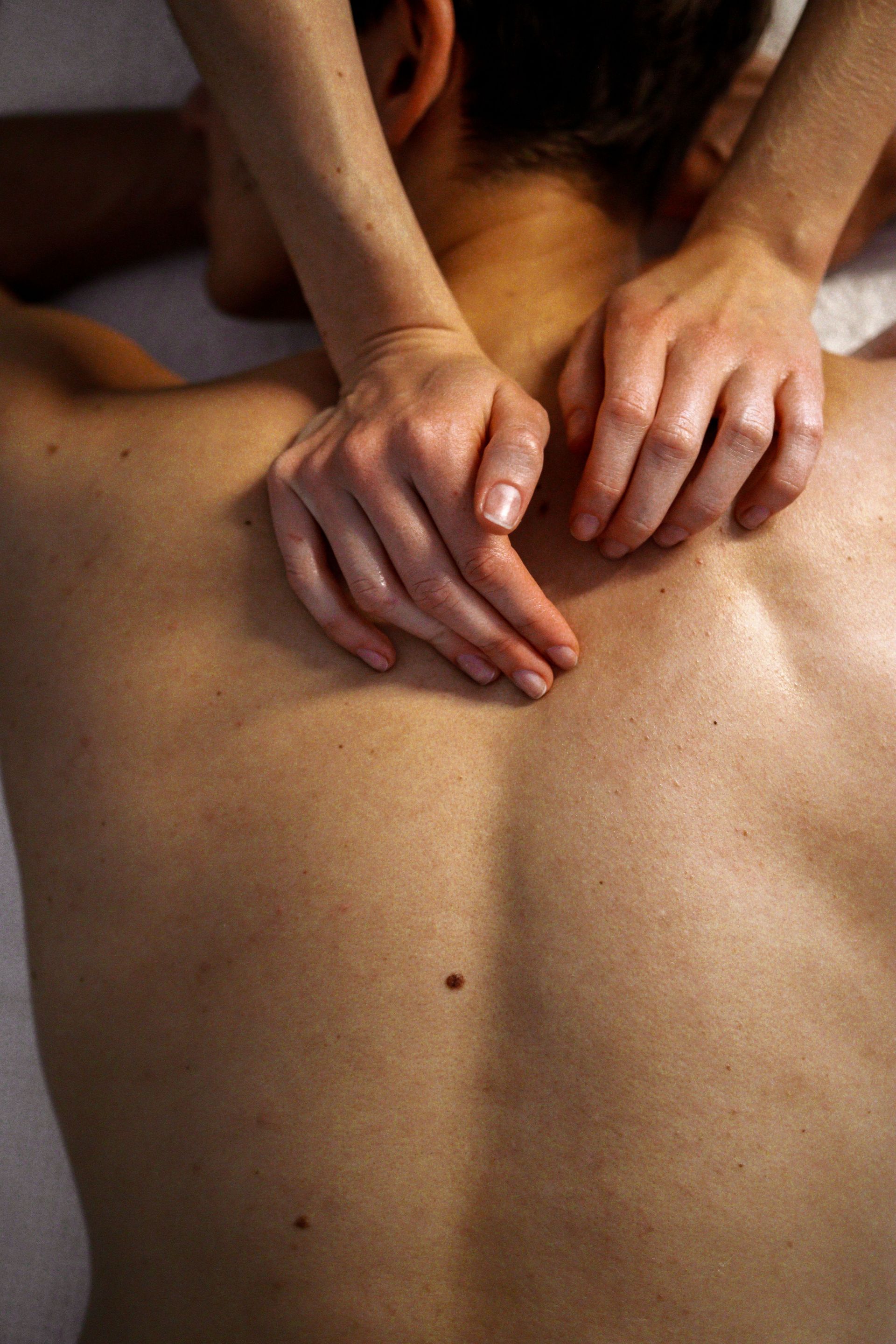 Des mains qui appuient et massent le dos nu d’une personne pendant un massage