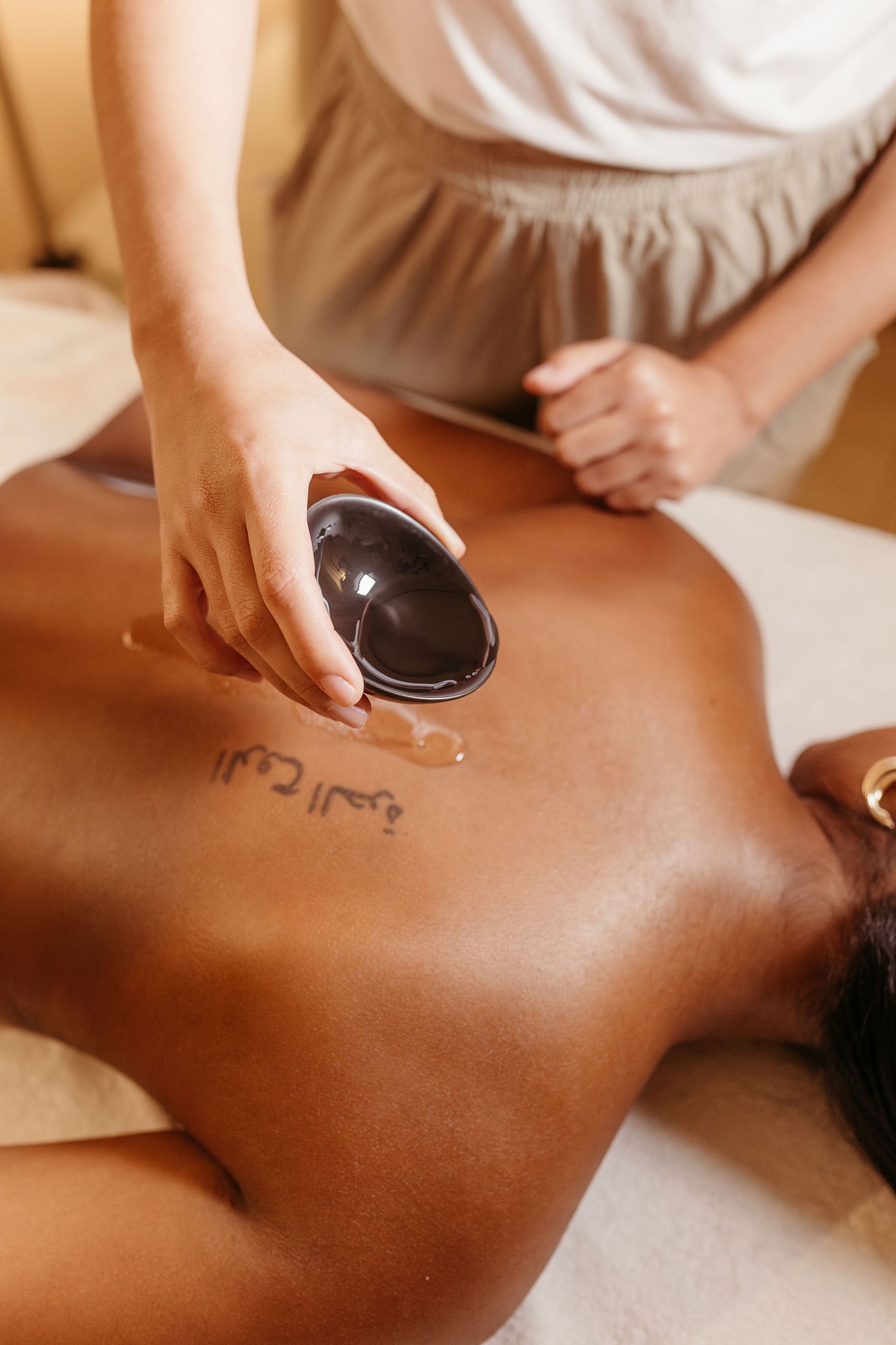 Un masseur utilisant une pierre chaude sur le dos d’une personne dans un spa