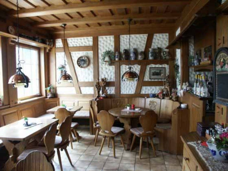 Blick in ein rustikal eingerichtetes Landhaus-Gasthauses mit Sitzecke, Holzstühlen und Messinglampen