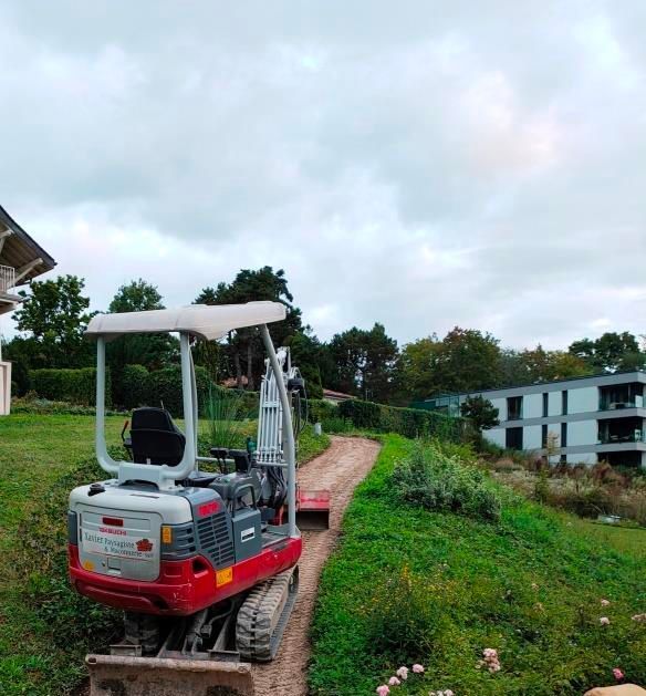Une excavatrice jaune creuse un trou dans un champ de terre.