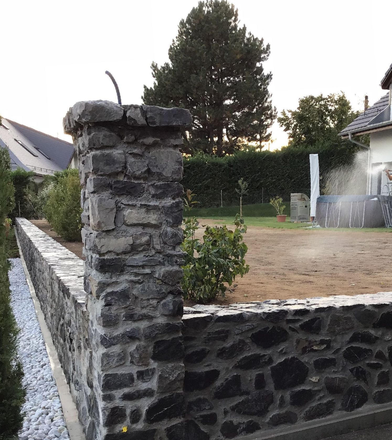 Une maison moderne avec un mur en béton et une passerelle en bois qui y mène.