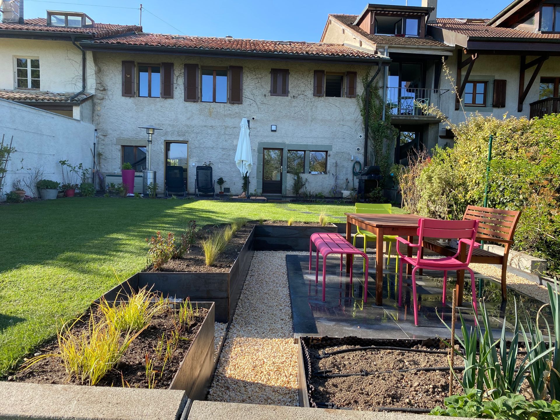 Une pelouse verte luxuriante avec une allée en briques menant à une maison en briques.