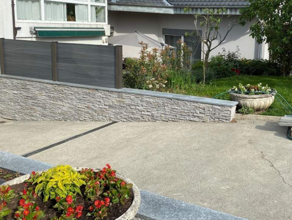 Une plante en pot avec des fleurs rouges et jaunes devant une maison