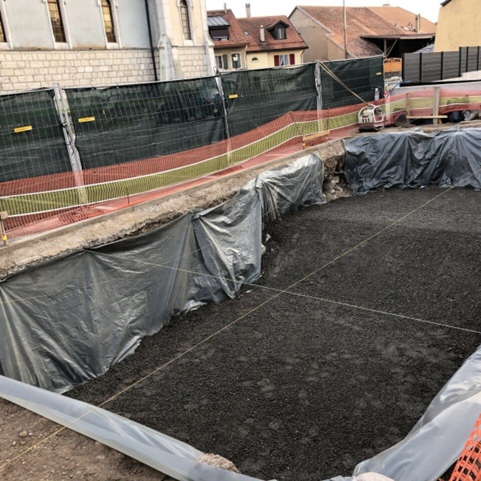 Un grand trou dans le sol est recouvert de plastique