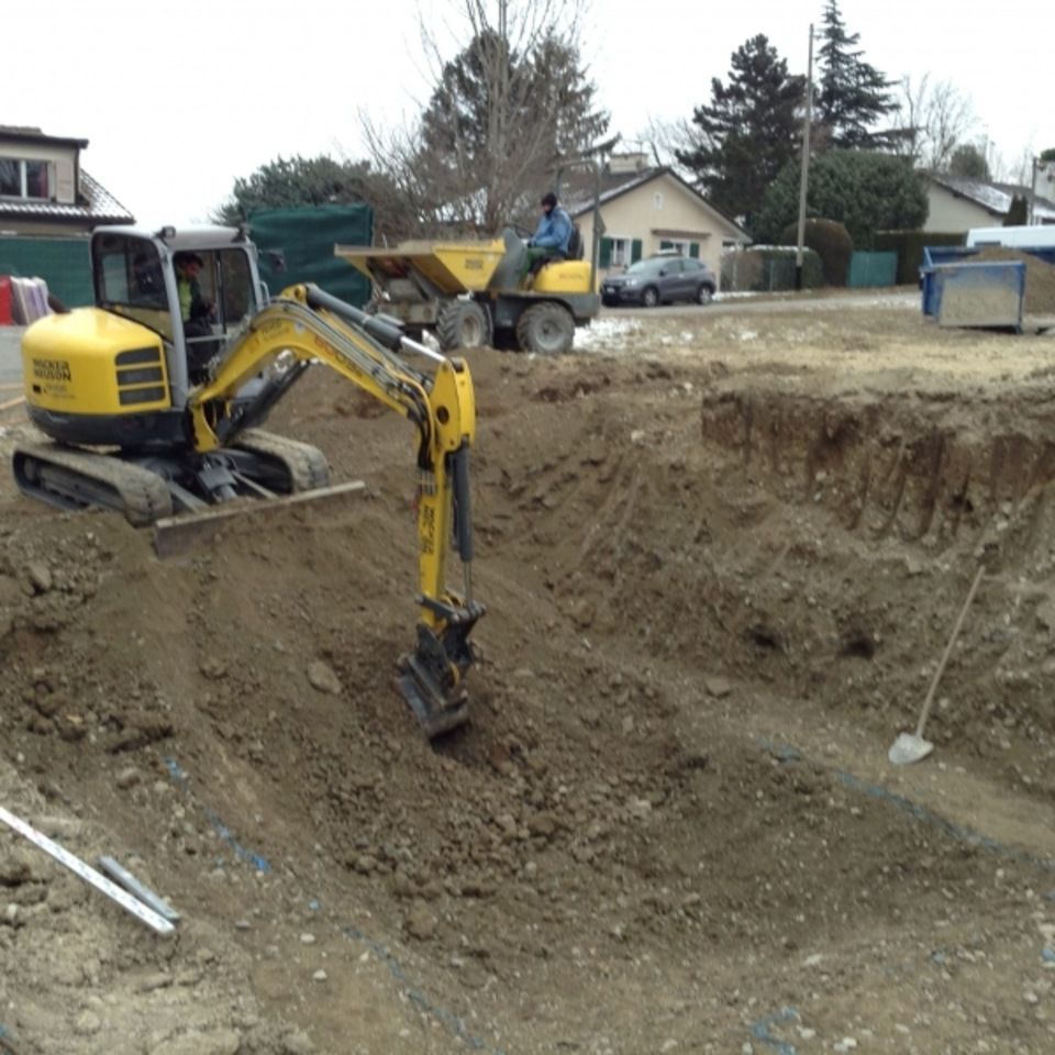 Une excavatrice jaune creuse un trou dans la terre
