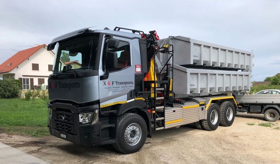 Un camion à benne basculante est garé sur le bord de la route à côté d'une maison.
