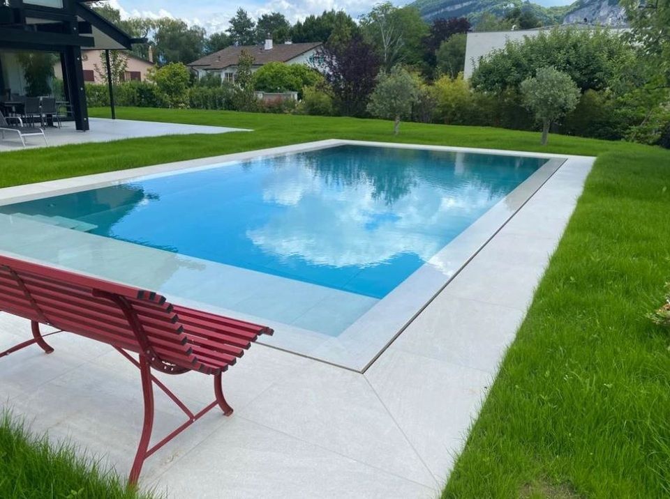 Une grande piscine avec un banc rouge devant