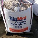 Una bolsa blanca llena de arena está encima de una paleta de madera.