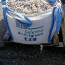 Una bolsa grande de grava está encima de una paleta de madera.