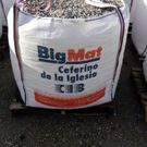 Una bolsa blanca llena de grava está encima de una mesa de madera.