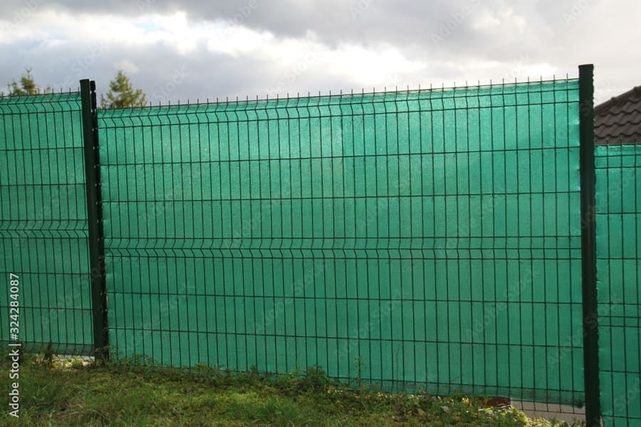 Una valla verde con una tela de sombra verde encima.