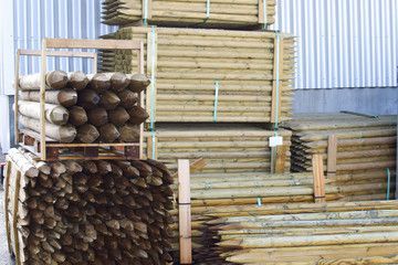 Una pila de postes de madera apilados uno encima del otro en un almacén.
