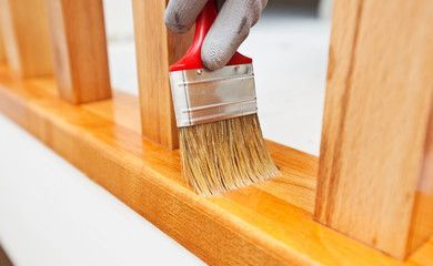 Una persona está pintando una barandilla de madera con un pincel.