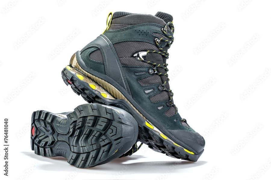 Un par de botas de montaña están apiladas una encima de otra sobre un fondo blanco.