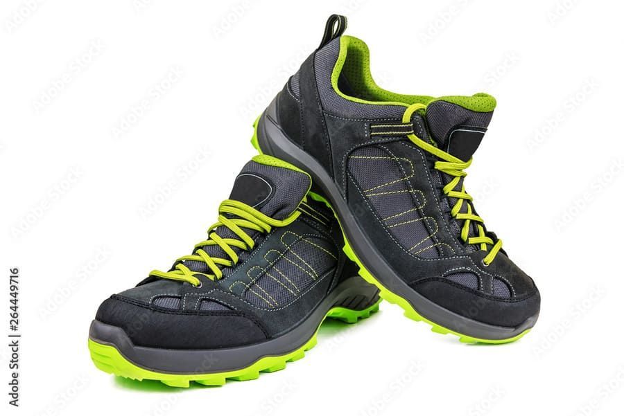 Un par de zapatos de senderismo negros y verdes sobre un fondo blanco.