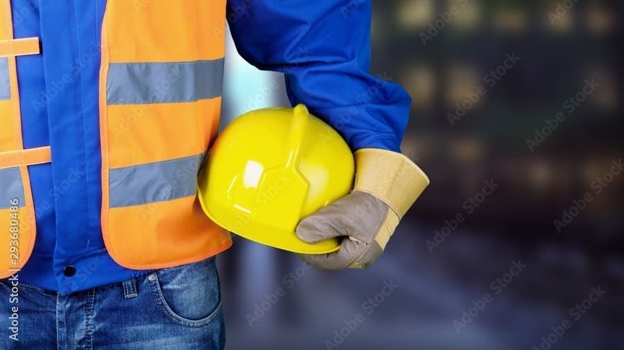 Un trabajador de la construcción sostiene un casco amarillo en su mano.