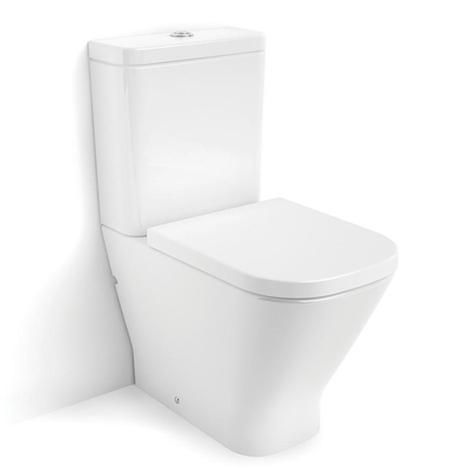 Un inodoro blanco está sentado al lado de una pared blanca.