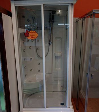 Una cabina de ducha con puertas corredizas de vidrio y un inodoro en un baño.