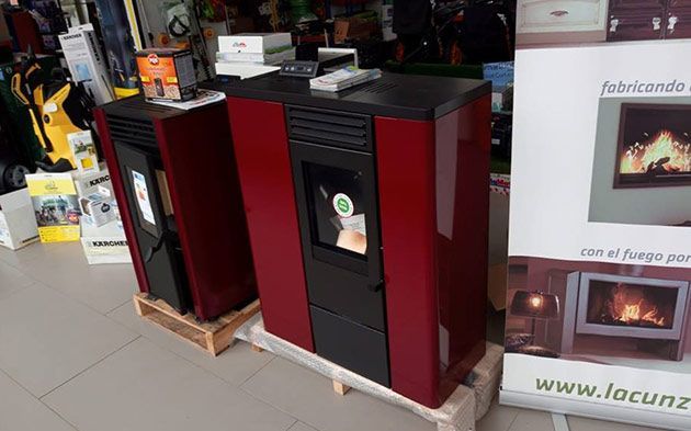 Una estufa roja y negra está colocada sobre una paleta de madera en una tienda.