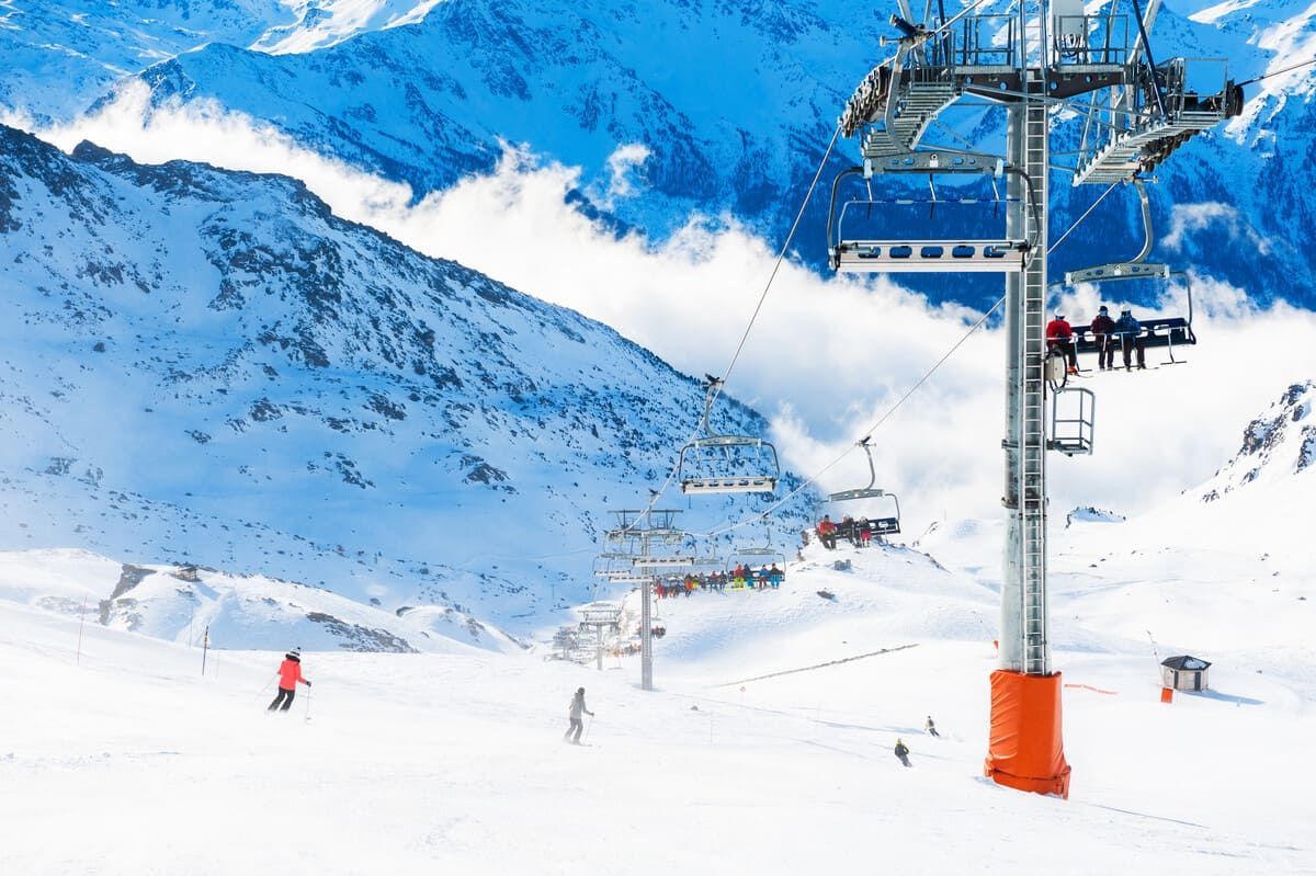 Casas y un camino frente a una cordillera bajo un cielo nublado.