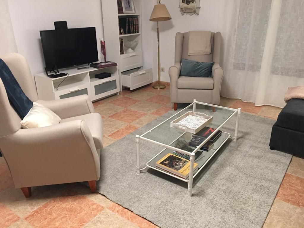 Sala de estar con dos sillones, mesa de centro, TV y estantería.
