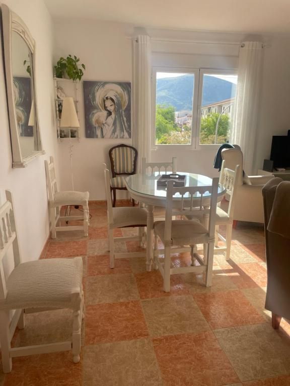 Sala de estar con mesa redonda, sillas blancas, obras de arte y vista a la montaña a través de la ventana.