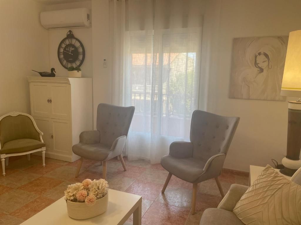 Sala de estar con dos sillones grises, un mueble blanco y una obra de arte enmarcada.