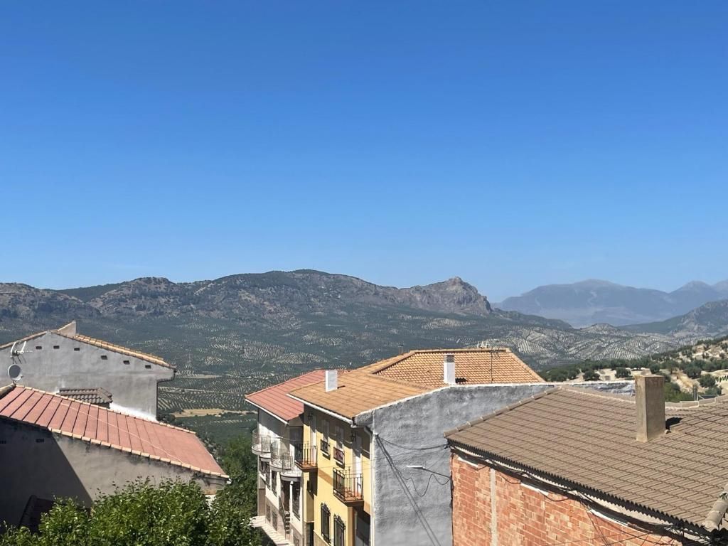 Los tejados de los edificios de un pueblo tienen vistas a una cadena montañosa bajo un cielo azul claro.