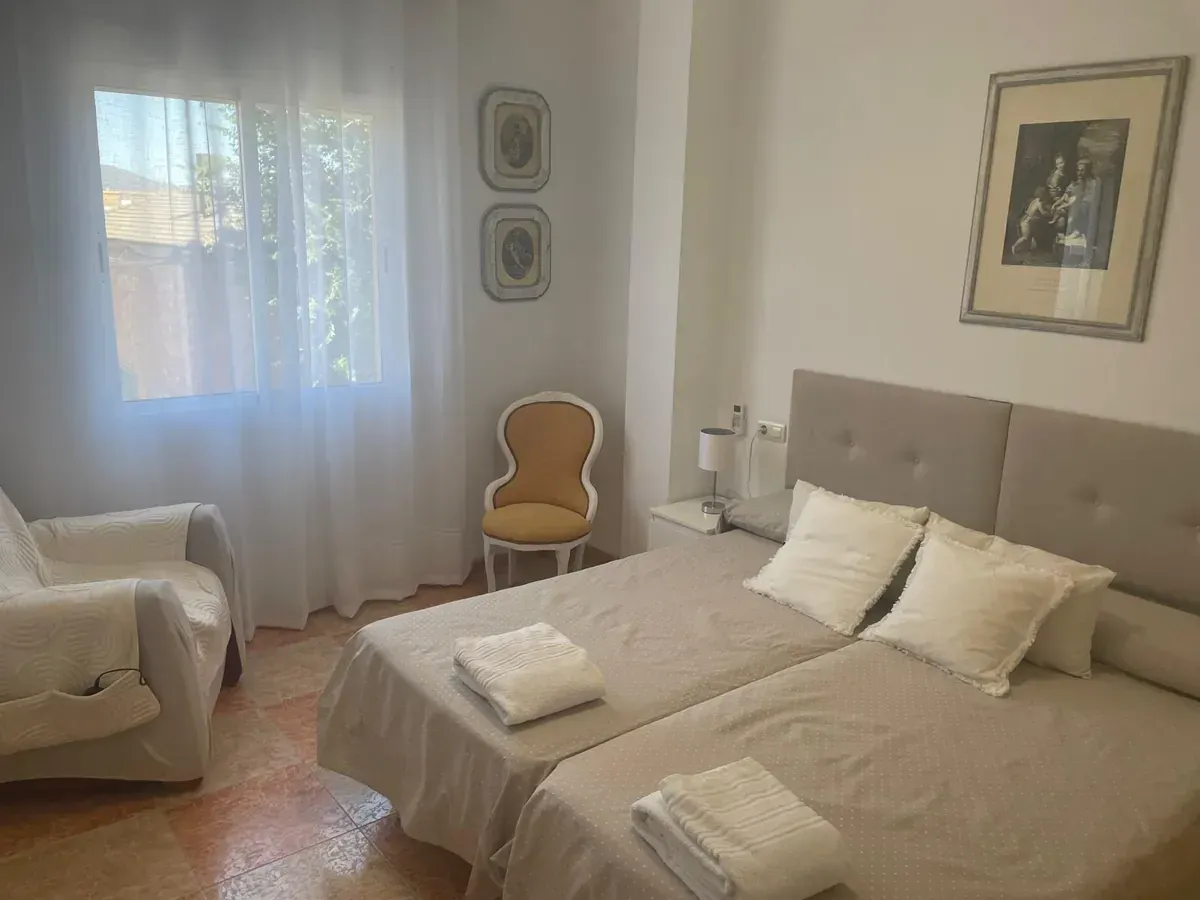 Escena junto a la piscina con piscina, tumbonas, sombrilla de paja, persona preparándose para nadar