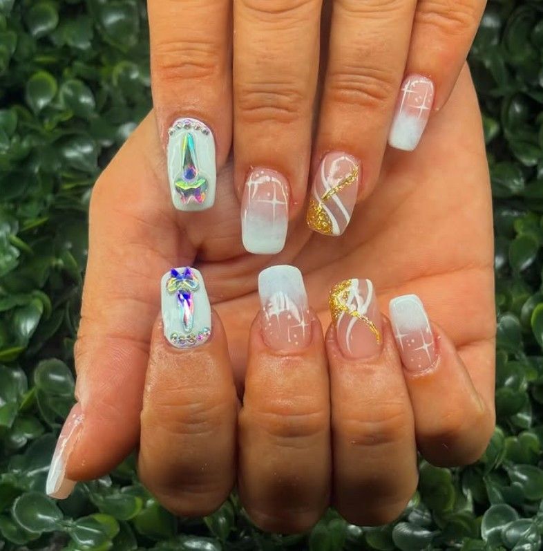 Manos con uñas largas en tonos pastel degradados y un diseño de mariposas brillantes sobre follaje verde.