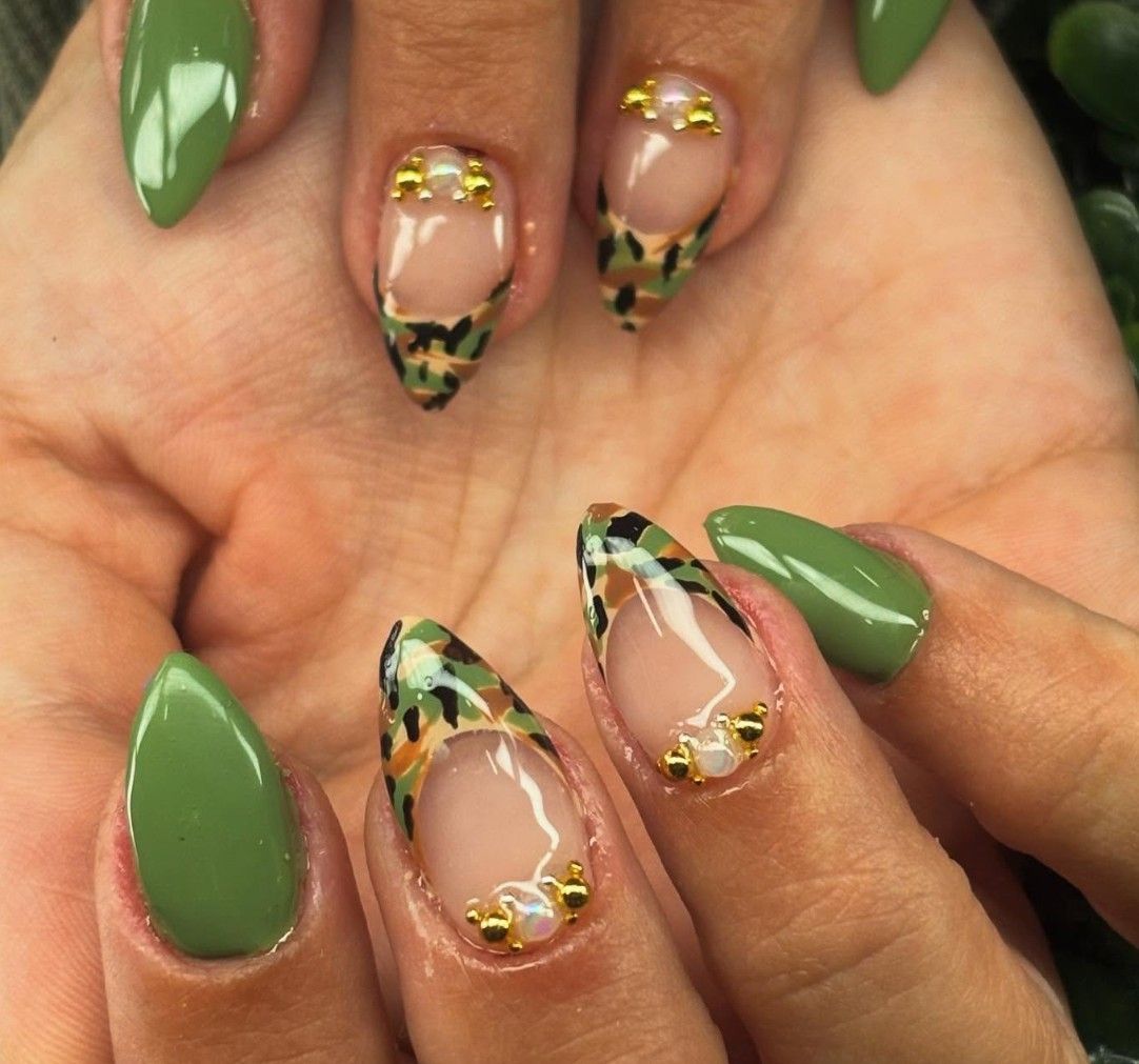 Manicura verde y carey con detalles dorados, mostrada en manos sobre un fondo de palma.