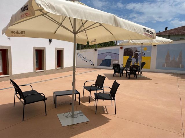 Una gran sombrilla blanca está encima de un patio con sillas y mesas.