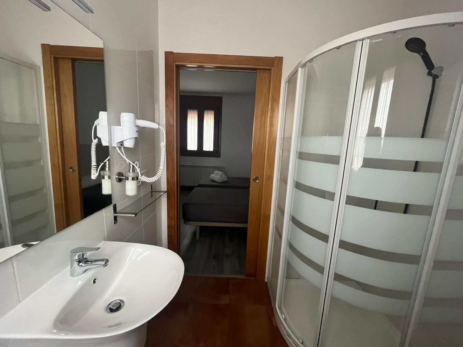 Un baño con lavabo, ducha y espejo.