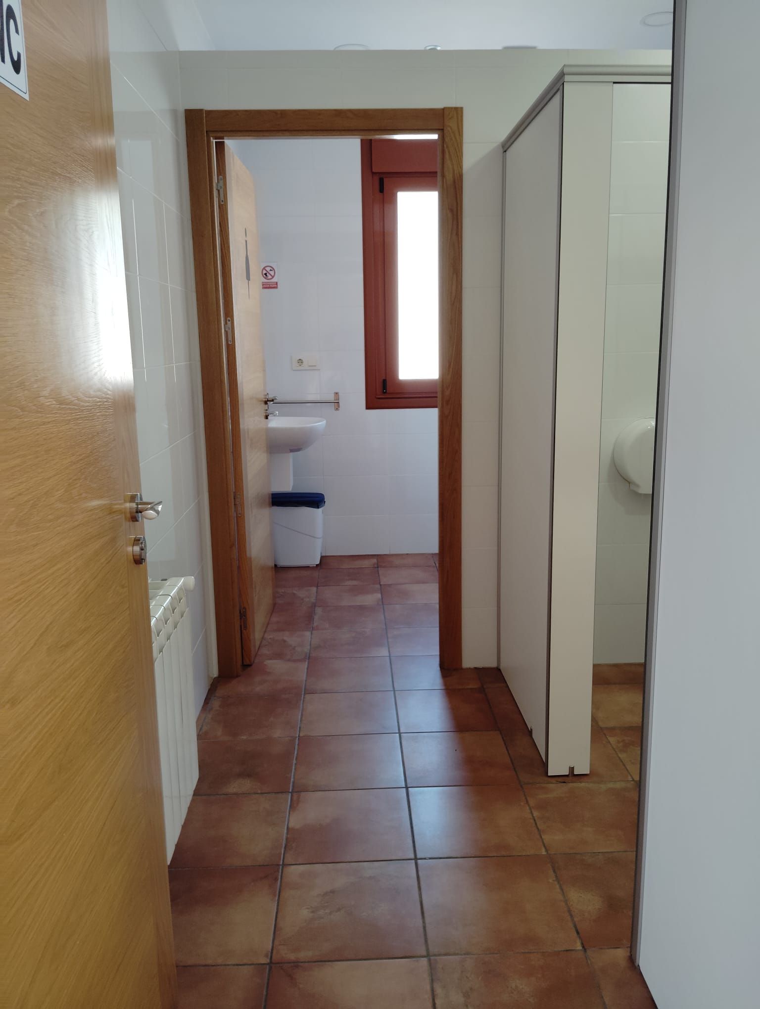 Un pasillo que conduce a un baño con lavabo y ventana.