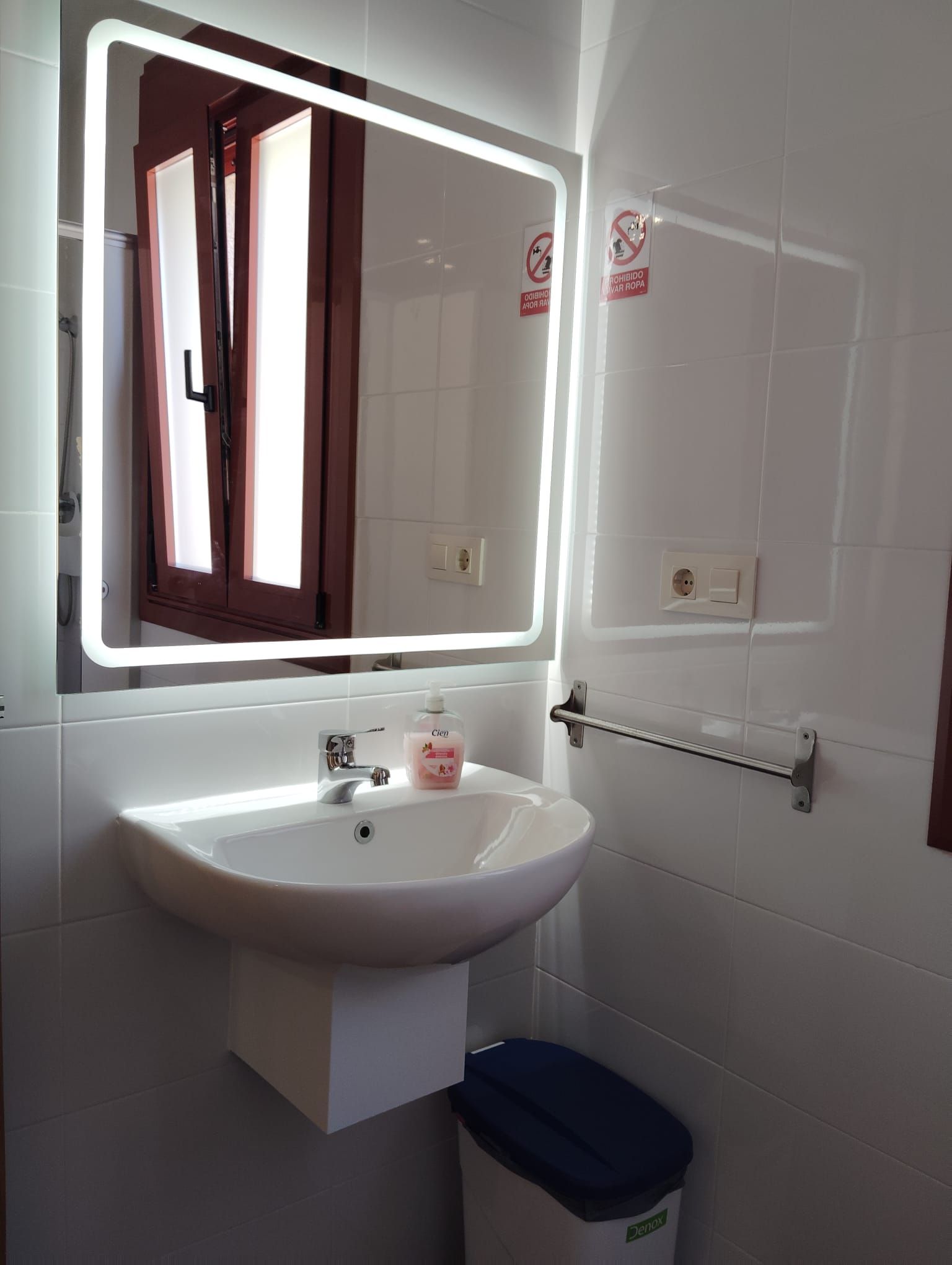 Un baño con lavabo, espejo y papelera.