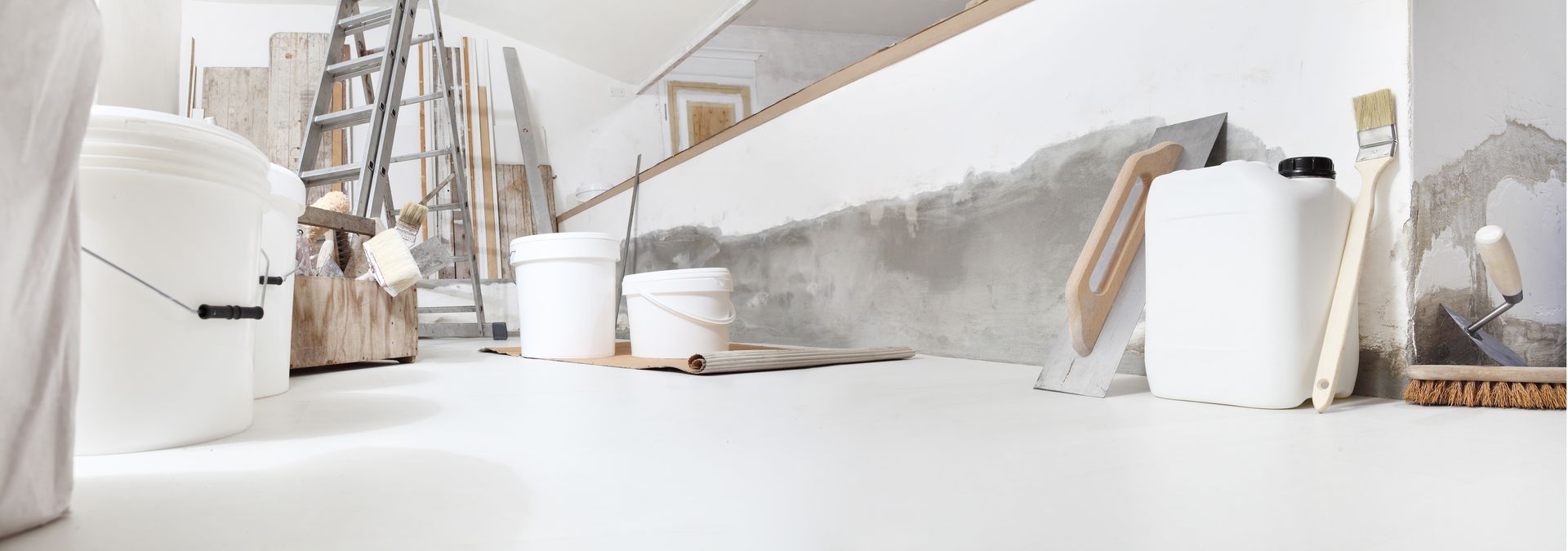 Une pièce en construction avec des seaux blancs, des outils et une échelle.