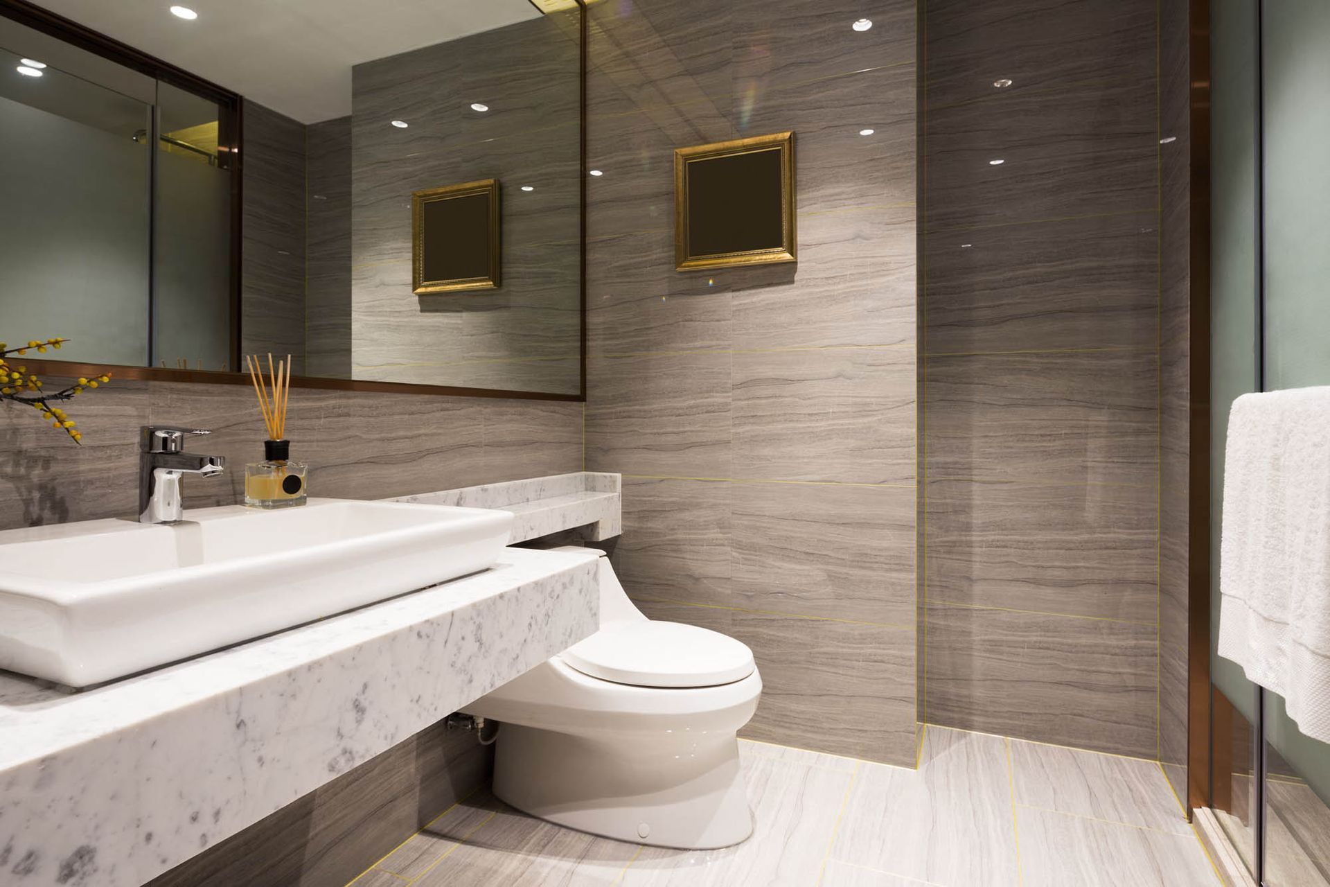 Ein Badezimmer mit Toilette, Waschbecken, Spiegel und ebenerdiger Dusche.
