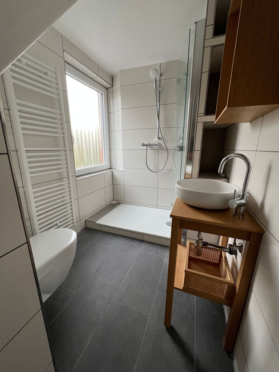 Ein Badezimmer mit Dusche, Waschbecken, WC , in einem kleinen verwinkeltem Bad