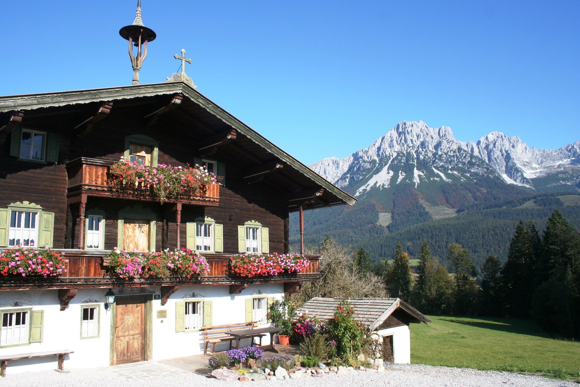a house with flowers on the balcony and mountains in the background