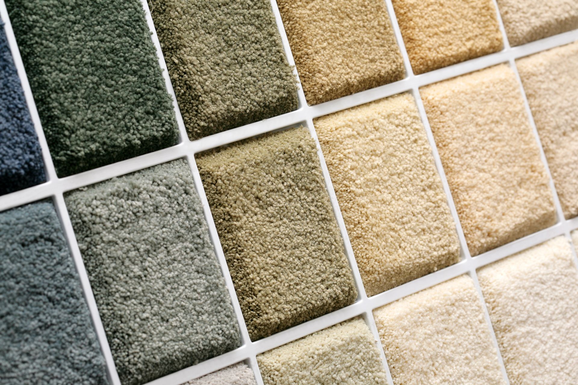 Échantillons de moquette gris, olive, beige et crème disposés en grille