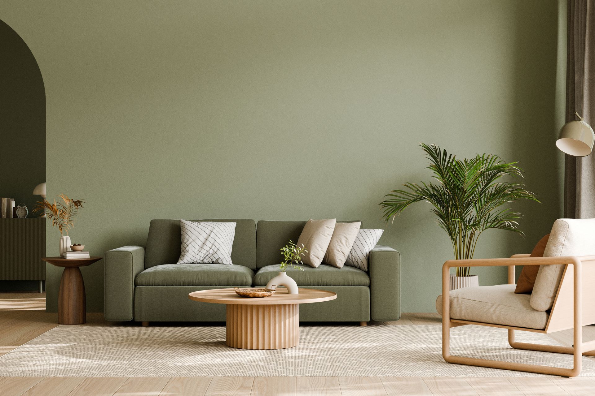 Salon minimaliste avec canapé olive, fauteuil en bois, table basse ronde, plante et décoration aux tons neutres et doux