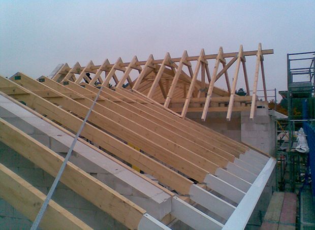 Die hölzerne Dachkonstruktion eines Gebäudes wird gerade errichtet.