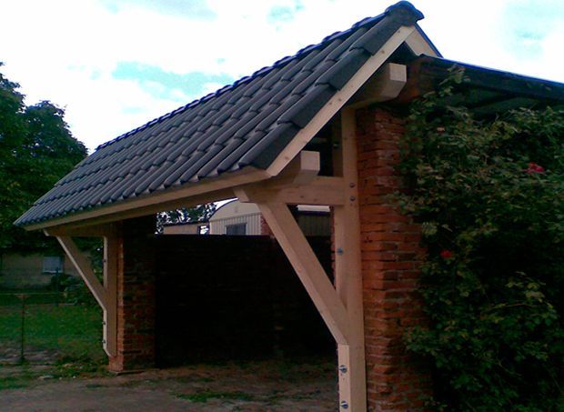 Carport mit Holzrahmen, roten Backsteinwänden und Ziegeldach.